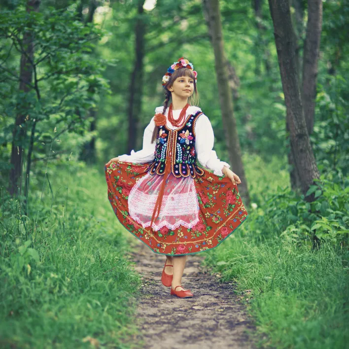 Dziewczynka w lesie w stroju ludowym trzyma spódnicę
